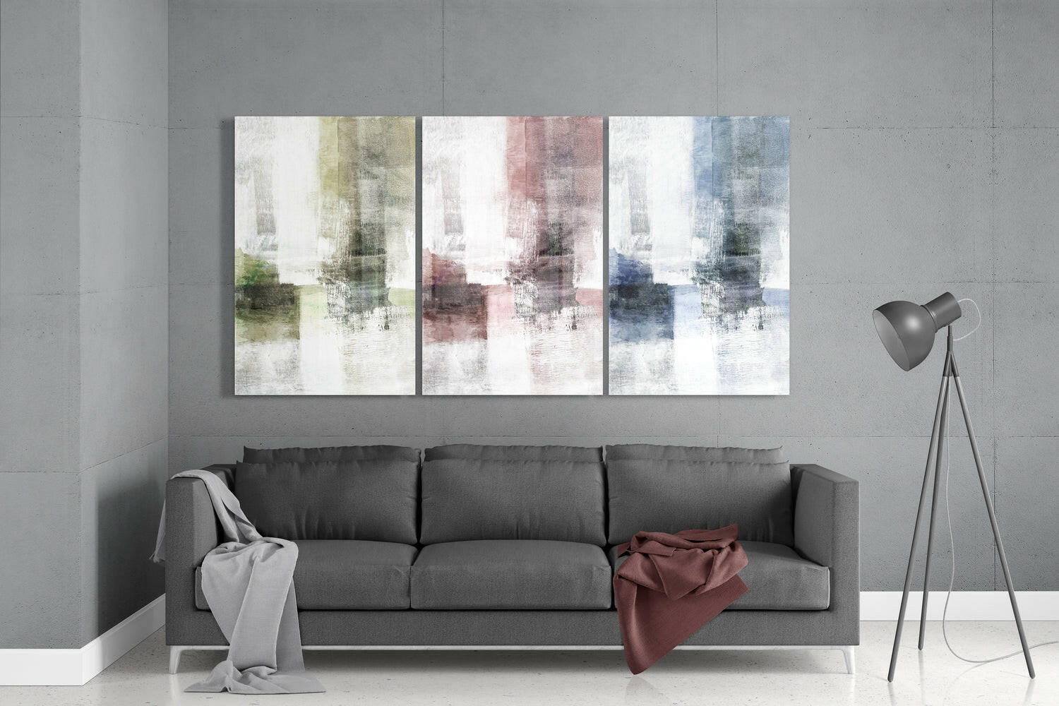 Modern living room with gray sofa displaying three pastel glass wall art panels in yellow, pink, and blue tones above it.