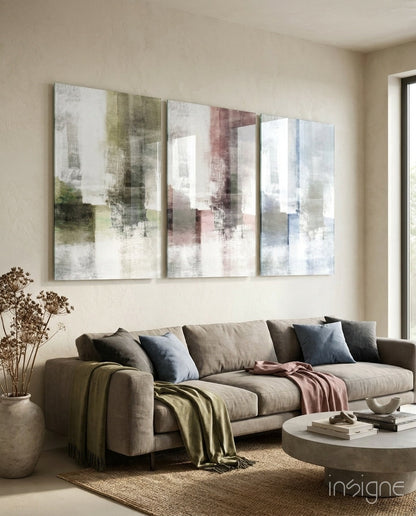 Three abstract glass panels with soft pastel colors in green, pink, and blue tones hung above a beige sofa in a modern living room.