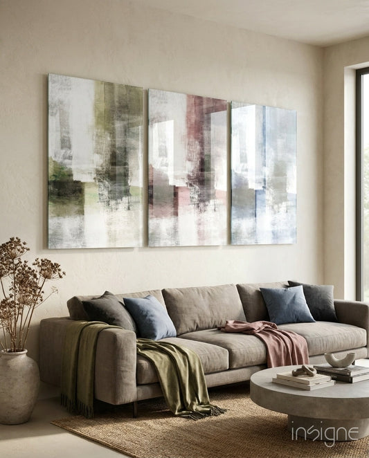 Three abstract glass panels with soft pastel colors in green, pink, and blue tones hung above a beige sofa in a modern living room.