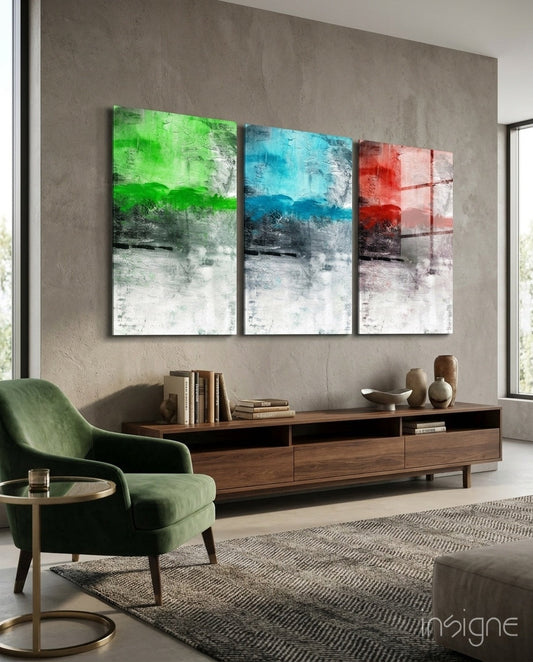Three framed abstract glass panels in green, blue, and red hanging above a wooden console in a modern living room interior.