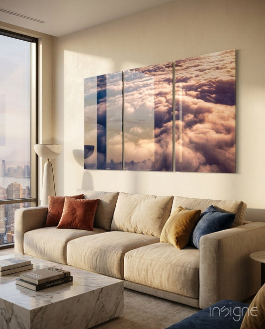 Multi-panel glass wall art depicting golden clouds above cityscape, installed above cream sofa in modern high-rise apartment.