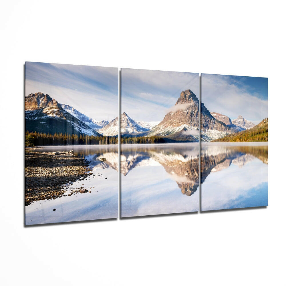 Three-panel glass wall art displaying snow-capped mountains reflected in a still alpine lake surrounded by evergreen forest.