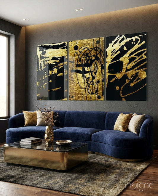 Three gold and black abstract glass panels with gestural marks displayed above a blue velvet sofa in a modern living room.