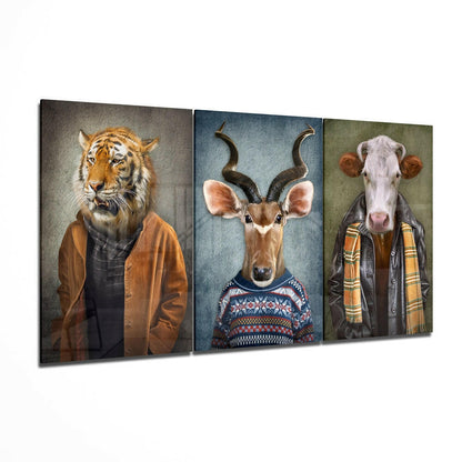 Three-panel glass wall art displaying anthropomorphized animal heads wearing human clothing: tiger in brown jacket, antelope with curved horns in patterned sweater, and cow in plaid shirt and jacket.