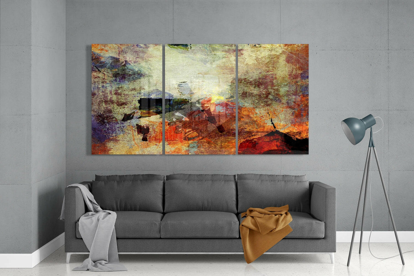 Three-panel abstract glass wall art with rust, orange, and gold tones displayed above gray sofa in modern living room.