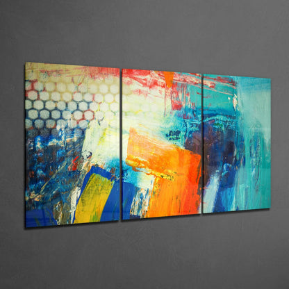 Three-panel glass wall art with abstract colorful brush strokes in blue, orange, yellow, and turquoise displayed on gray wall.
