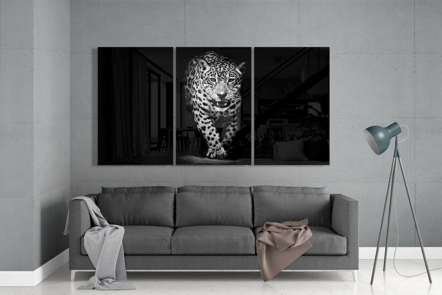 Three-panel black and white glass wall art displaying a leopard in the center panel, mounted above a gray sofa in a minimalist interior.