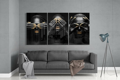 Three black glass panels with gold-accented faces and hands displayed above gray sofa in modern living room interior.