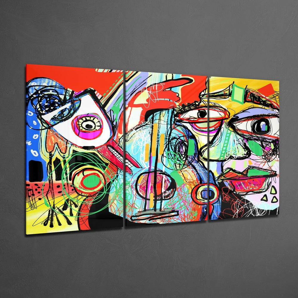 Three-panel abstract glass wall art displaying vibrant multi-colored faces with expressive eyes against red, yellow, and blue backgrounds mounted on gray wall.