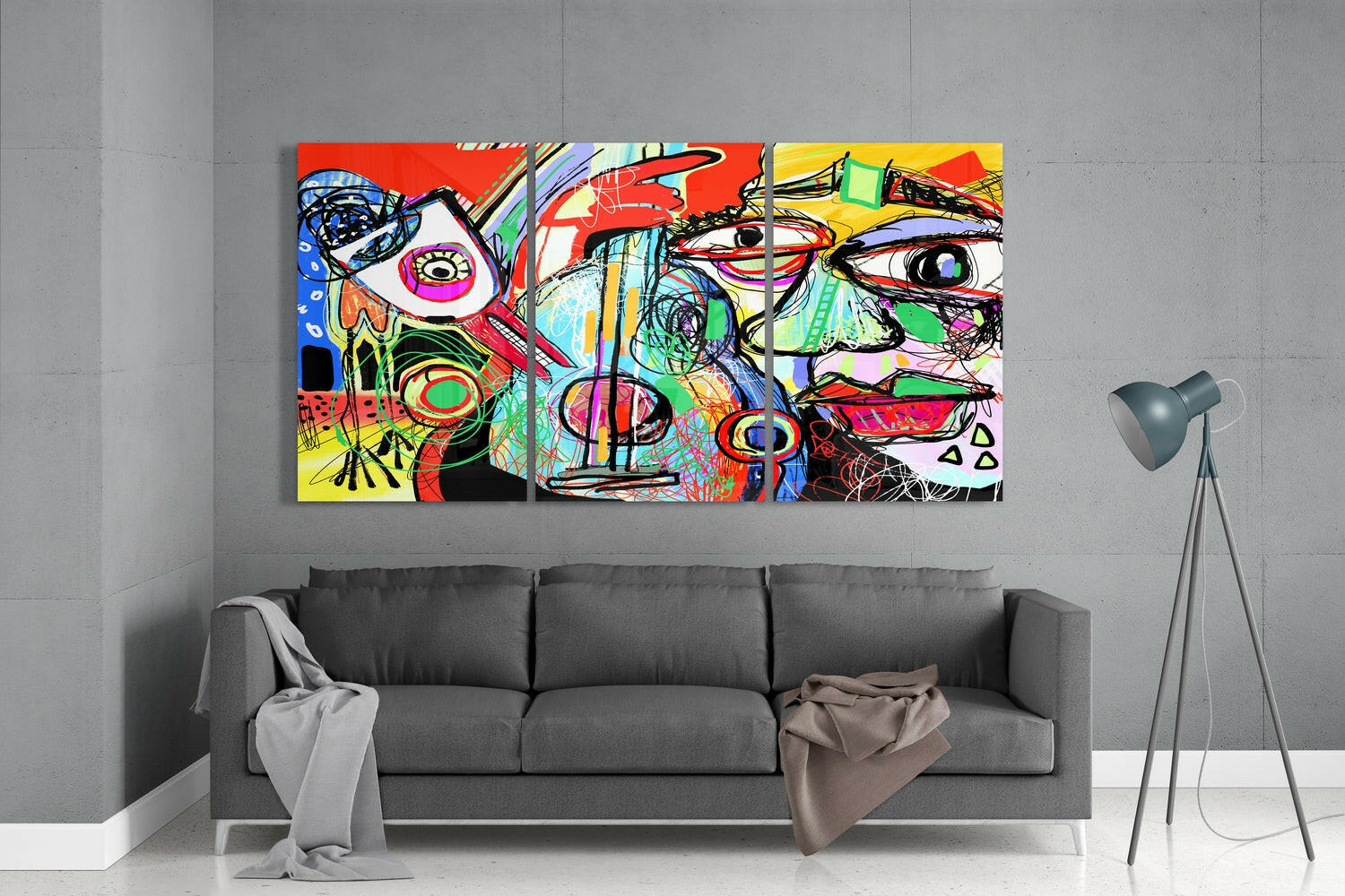 Vibrant abstract glass wall art triptych with colorful geometric faces displayed above gray sofa in modern interior.