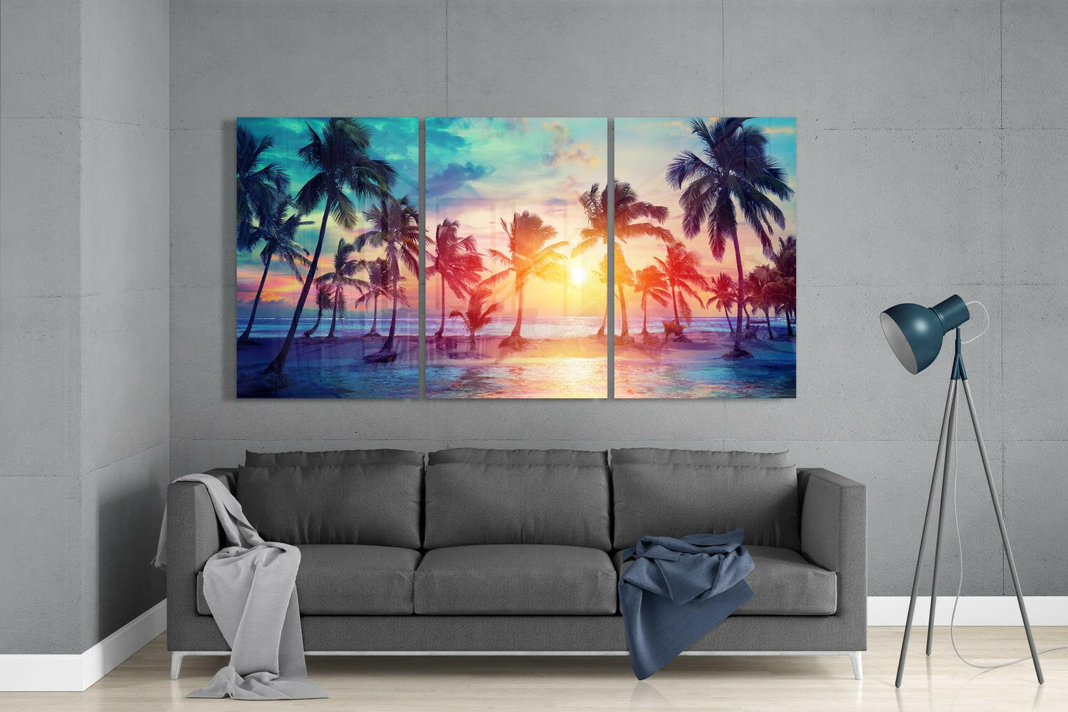 Three-panel tropical sunset glass art displaying palm trees and golden sunlight over water, displayed above gray sofa in modern living room.