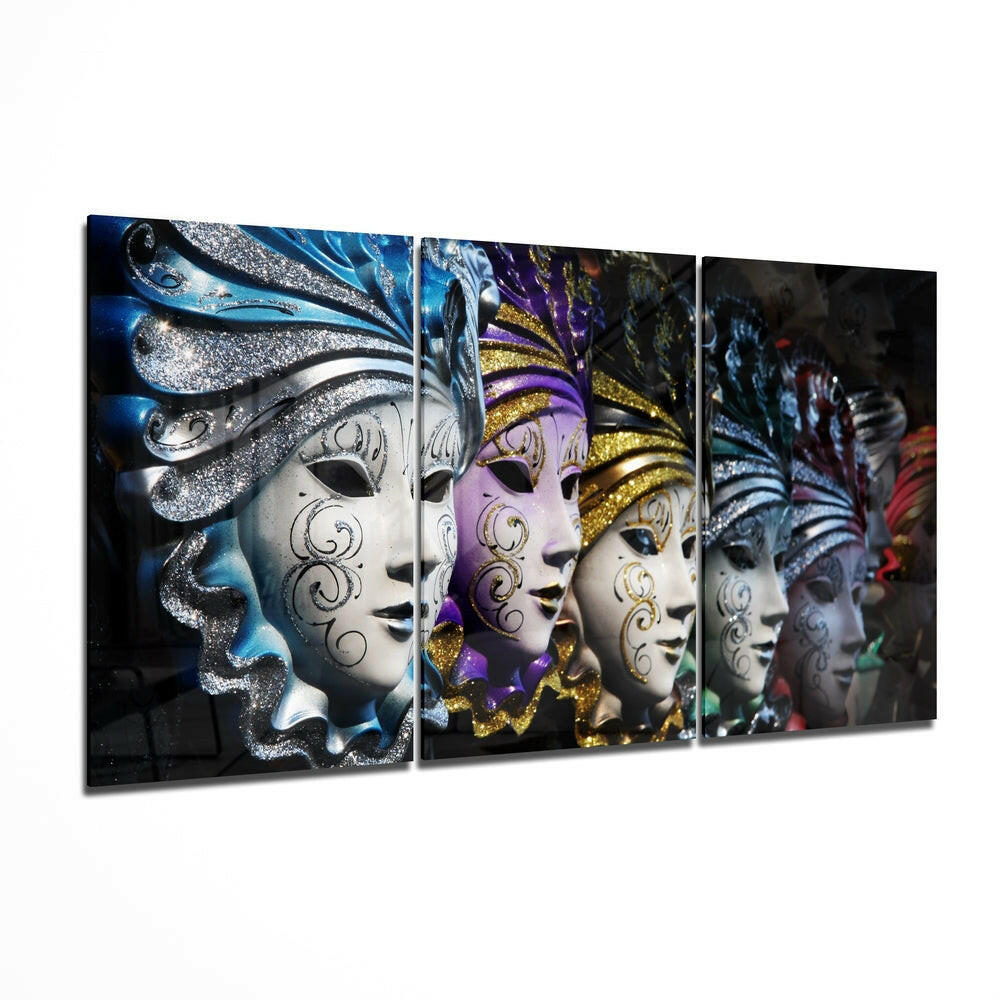 Three-panel glass wall art displaying ornate Venetian masks with silver, purple, and gold glitter embellishments against dark backgrounds, shown at an angled perspective.