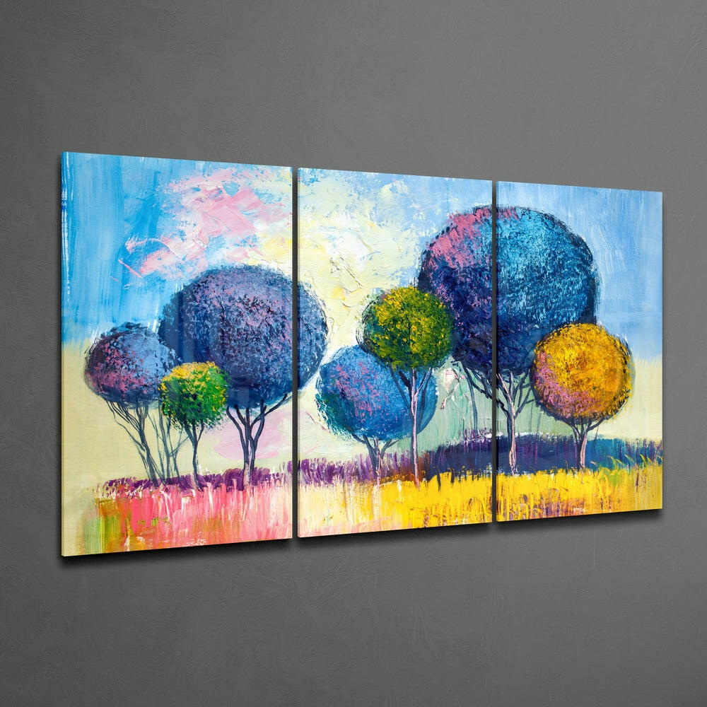 Three-panel glass wall art displaying colorful stylized trees with blue, purple, and yellow foliage against a vibrant landscape background.