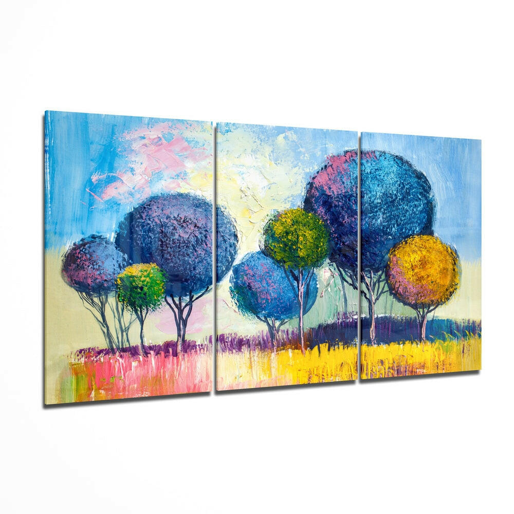 Three-panel glass wall art depicting colorful stylized trees with blue, purple, yellow, and pink foliage against a blue sky and yellow-pink grassland, displayed at an angle.