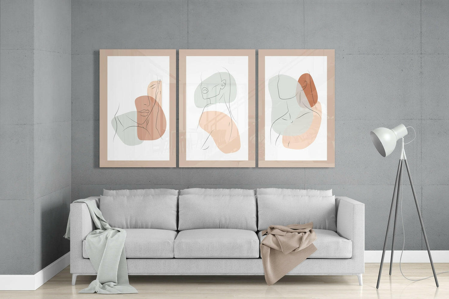 Three framed abstract portrait artworks with minimalist line drawings and soft watercolor shapes in beige and sage green tones hung above a light gray sofa.