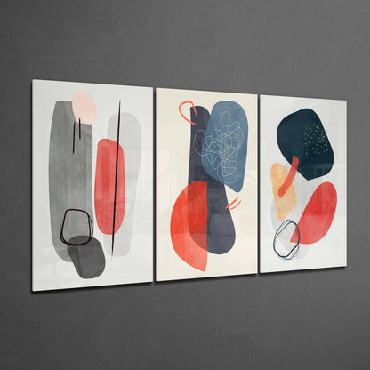 Three framed abstract glass wall art panels displaying geometric shapes in red, gray, blue, and black with line drawings on a textured gray wall.