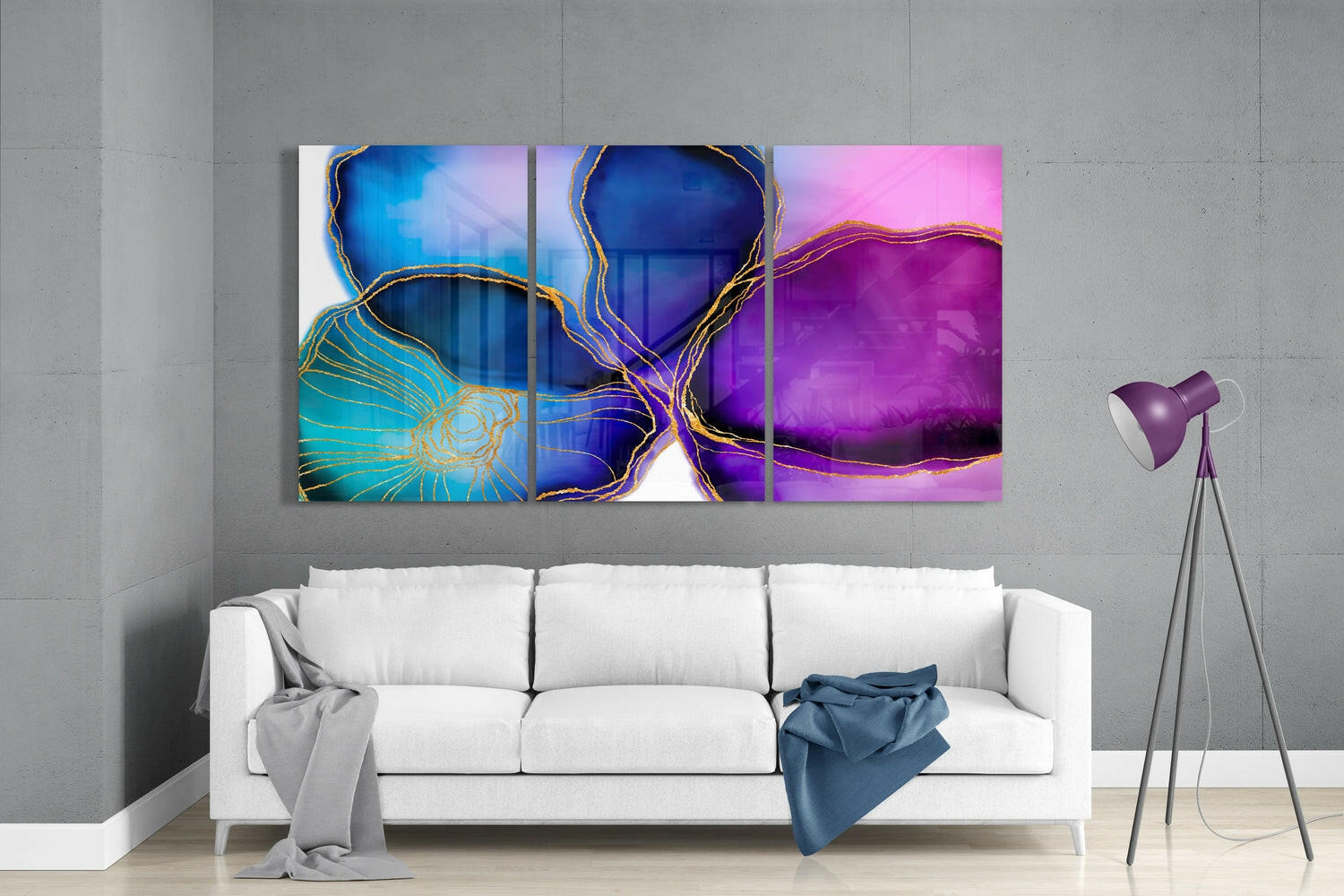 Modern living room with white sofa displaying three-panel abstract glass wall art featuring blue, purple, and gold swirling designs above.
