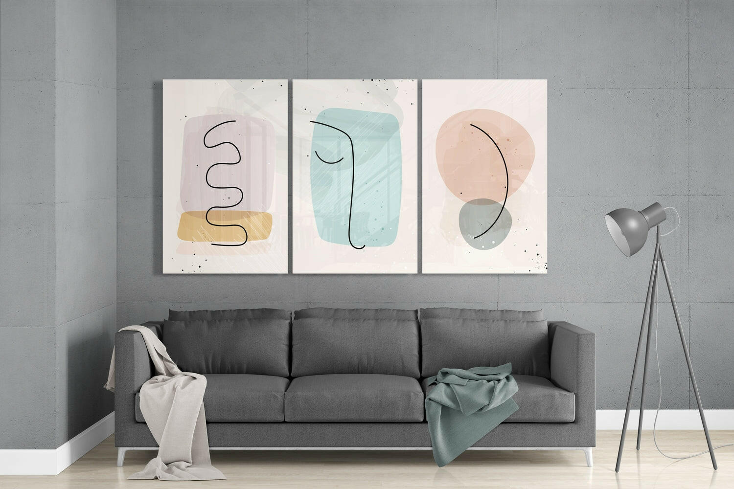 Three abstract glass wall art panels with pastel shapes and line drawings displayed above a gray sofa in a modern living room.