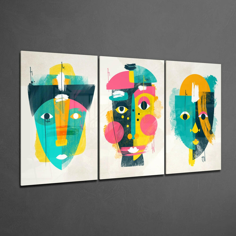 Three framed glass panels displaying abstract geometric faces in turquoise, yellow, pink, and orange on cream background, mounted on gray wall.