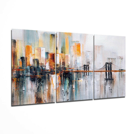 Three-panel abstract canvas art displaying a cityscape with bridge, featuring warm amber and cool blue tones with vertical brushstrokes, displayed at an angle.