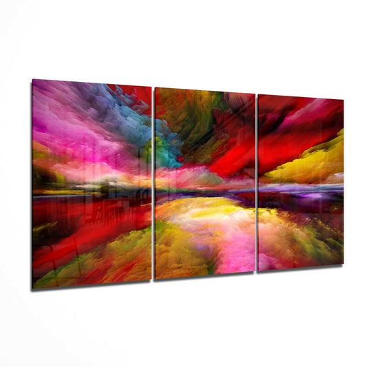 Three-panel glass wall art displaying an abstract landscape with vibrant swirling colors of magenta, red, yellow, and blue, shown at an angled perspective.