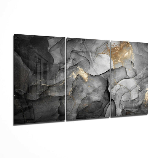 Three-panel glass wall art with abstract grayscale swirls and gold accents on dark background, displayed at angle.