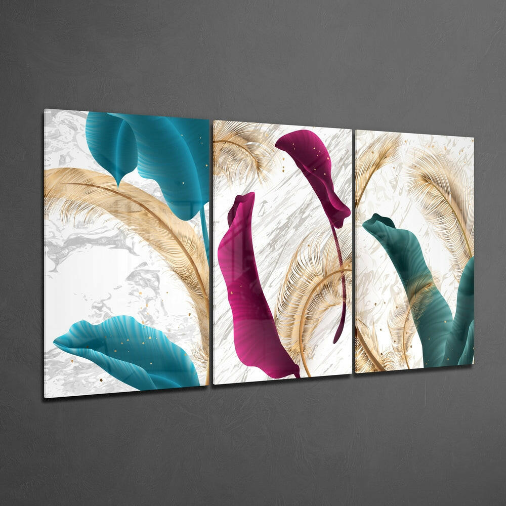 Three-panel glass wall art displaying teal, magenta, and teal stylized leaves with gold botanical details on white textured background, mounted on gray wall.