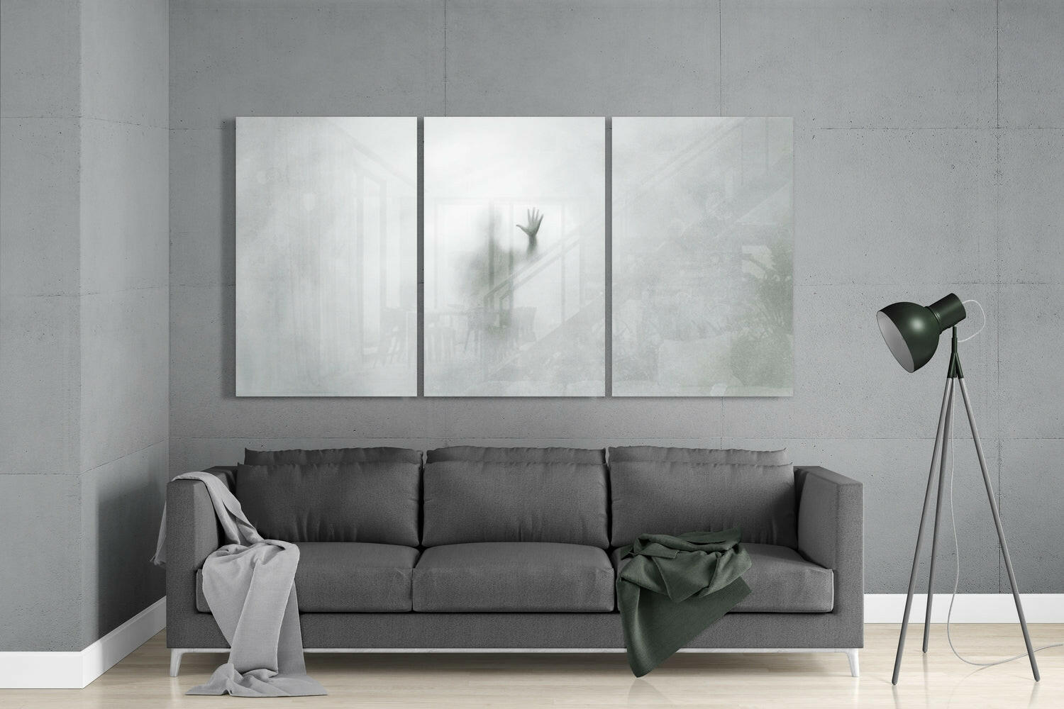 Modern living room interior with gray sofa beneath three frosted glass panels displaying blurred hand and architectural imagery.