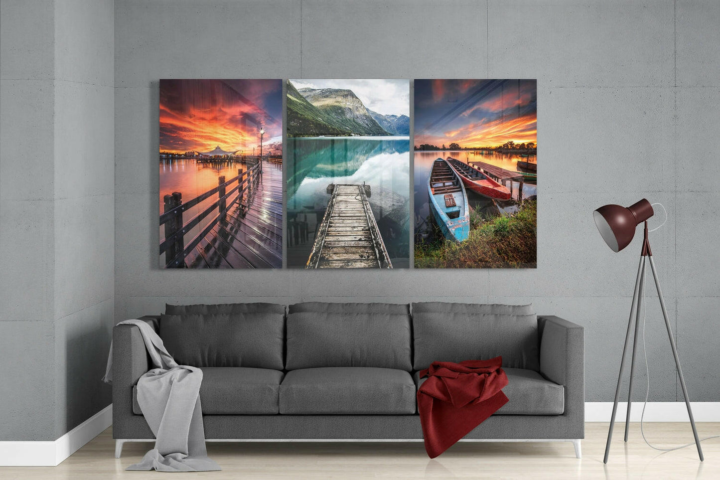 Three glass wall art panels displaying sunset piers and lakeside scenes hung above a gray sofa in a modern living room.