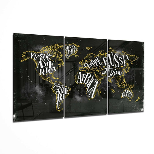 Three-panel glass wall art with gold-outlined world map on black background, white typography labeling continents, displayed at an angle.