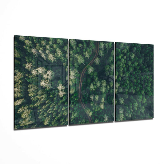Three-panel glass wall art displaying an aerial forest view with a winding red road cutting through dense green trees, shown at an angle against a white background.
