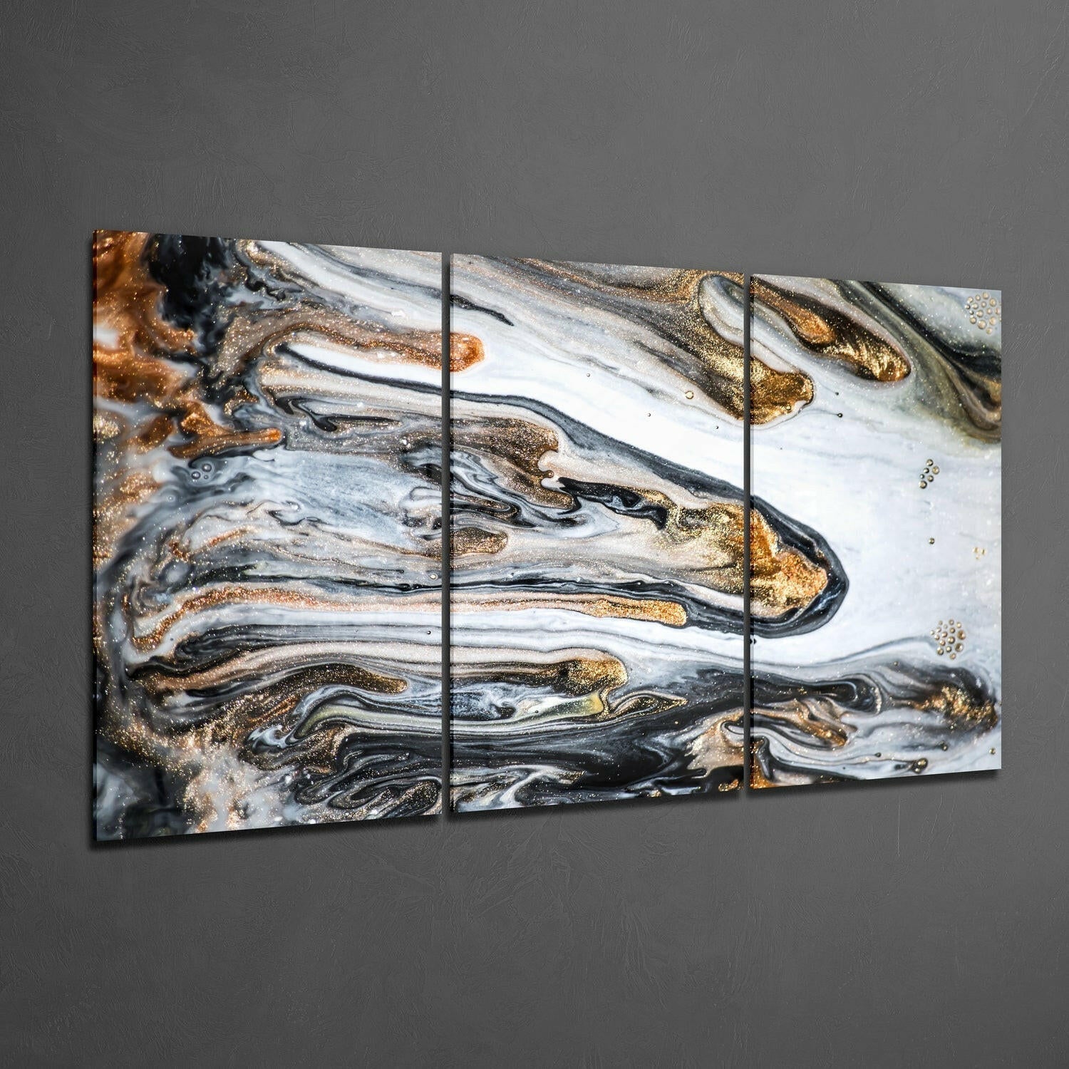 Three-panel glass wall art displaying abstract marbled design in black, white, gold, and bronze swirled patterns mounted on gray wall.