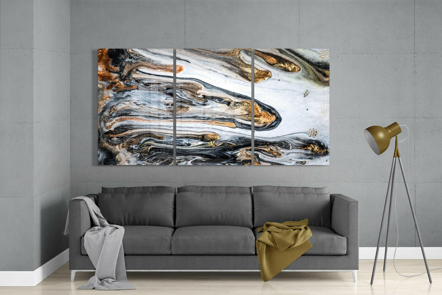 Three-panel glass marbling wall art in black, white, and gold tones displayed above a gray sofa in a modern living room.