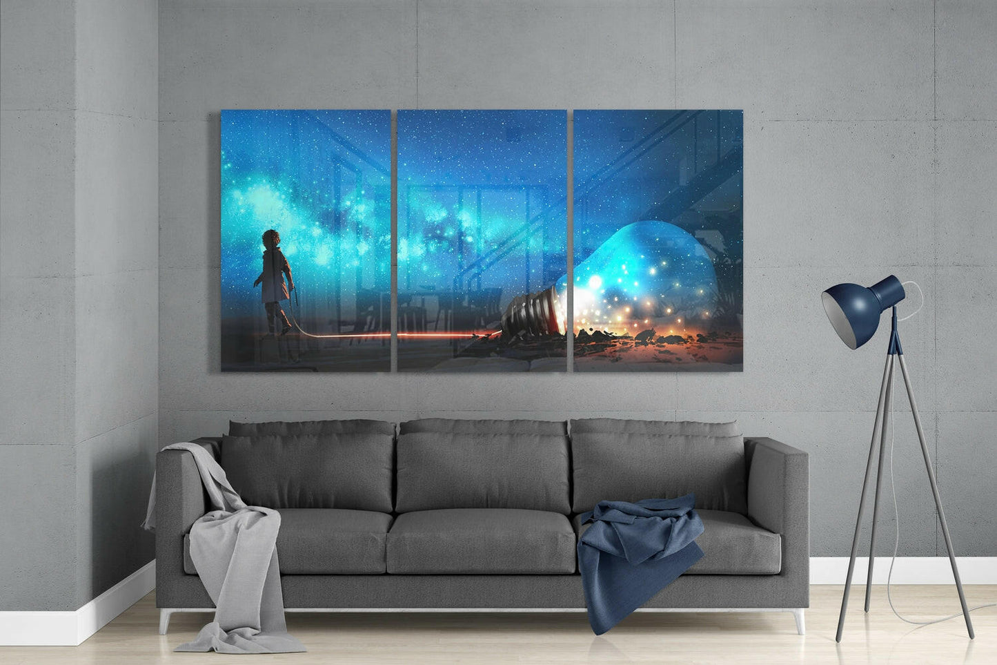 Three-panel glass wall art above gray sofa depicting silhouetted child, glowing light bulb, and starry blue cityscape with warm orange ground lighting.