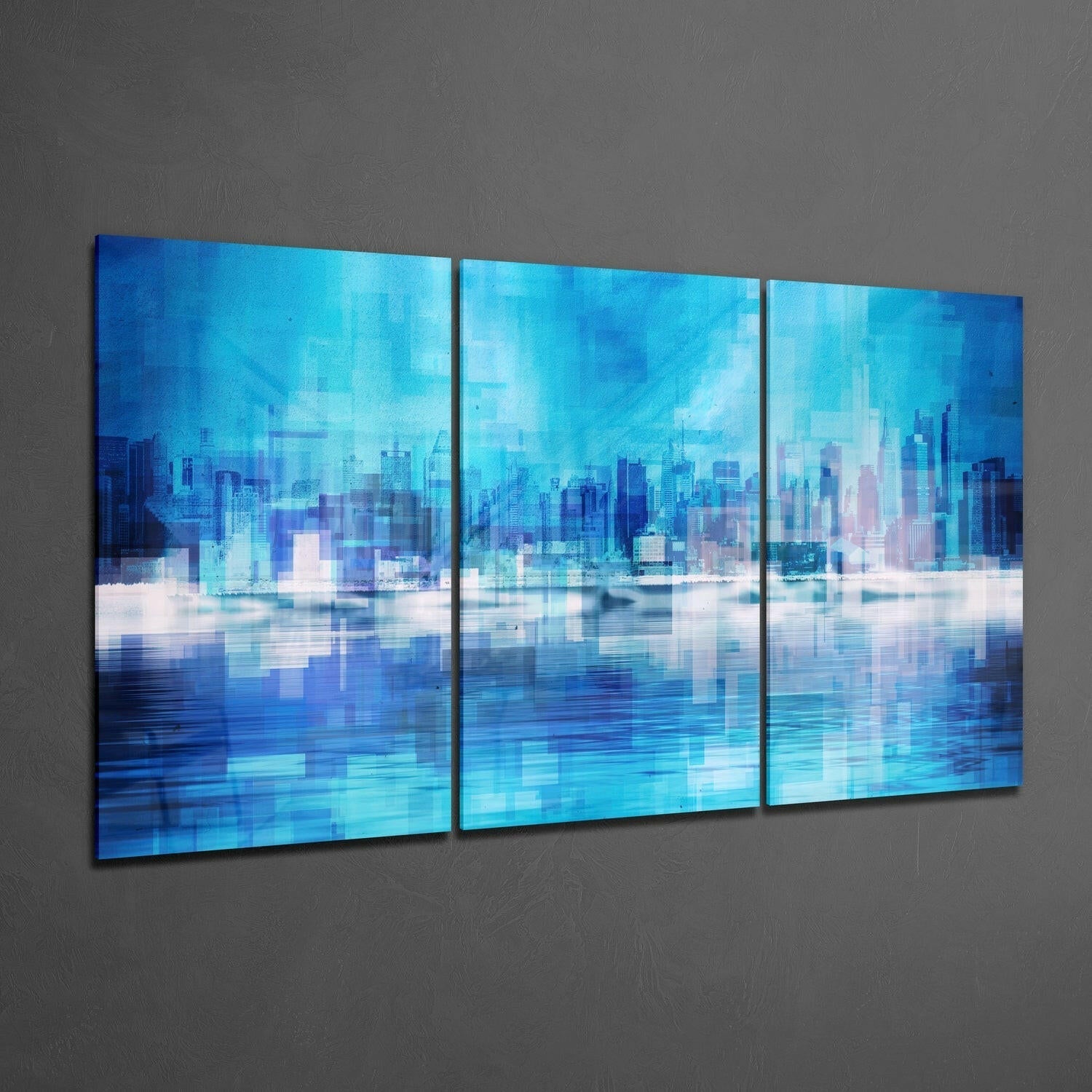 Three-panel blue glass wall art displaying a layered cityscape with waterfront reflection mounted on gray wall.