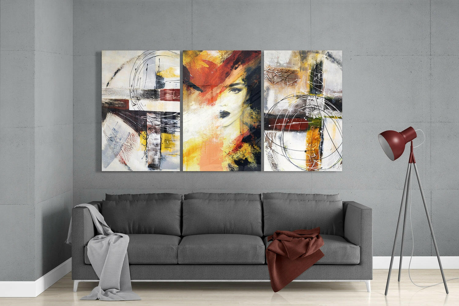 Three abstract glass wall panels with colorful portraits and geometric shapes hung above a gray sofa in a modern living room.
