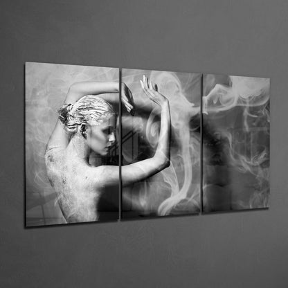 Three-panel black and white glass wall art displaying a shirtless figure in profile with flowing fabric, mounted on gray wall.