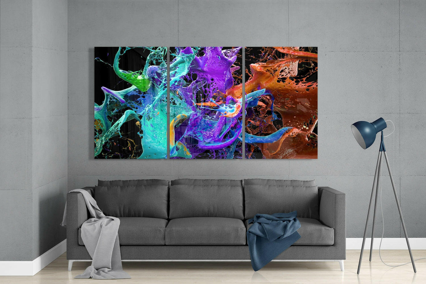 Colorful abstract glass wall art triptych with vibrant cyan, purple, and orange swirling patterns displayed above gray sofa in modern interior.