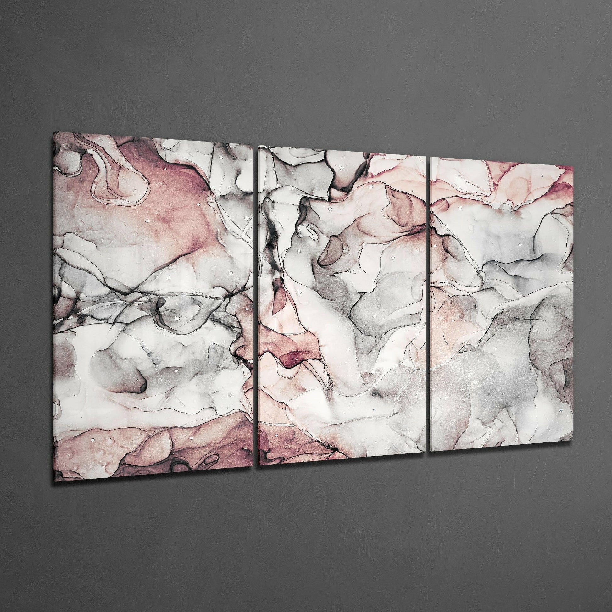 Three-panel glass art display with swirling pink, gray, and black marbled patterns on white background mounted on gray wall.