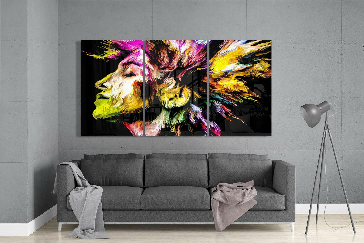 Colorful Peace glass art triptych displaying vibrant yellow, pink, and magenta profiles hung above gray sofa in minimalist interior.