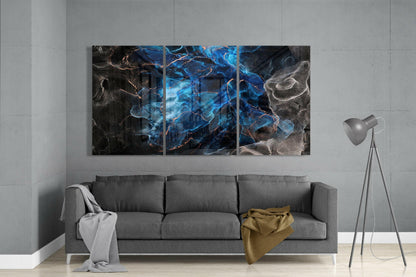 Three-panel blue and black glass art installation mounted above gray sofa in minimalist living room interior.
