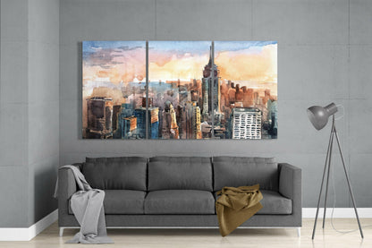 Three-panel watercolor Manhattan skyline glass art above gray sofa in modern interior setting.