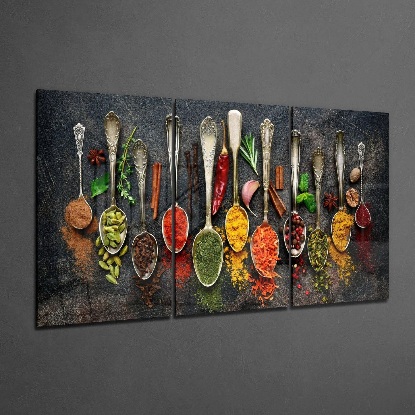 Three-panel glass art displaying ornate spoons filled with colorful spices and fresh herbs on dark textured background.