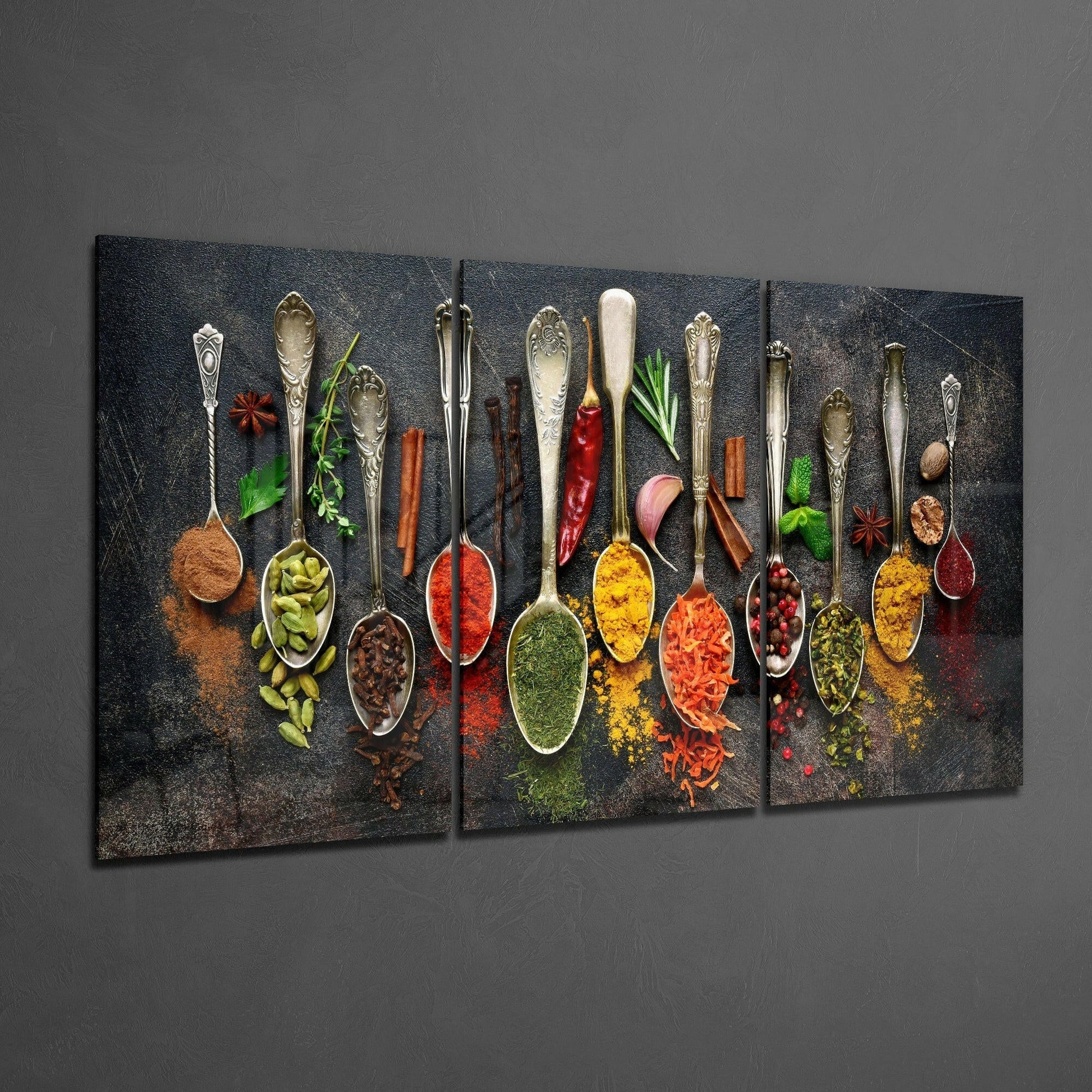 Three-panel glass art displaying ornate spoons filled with colorful spices and fresh herbs on dark textured background.