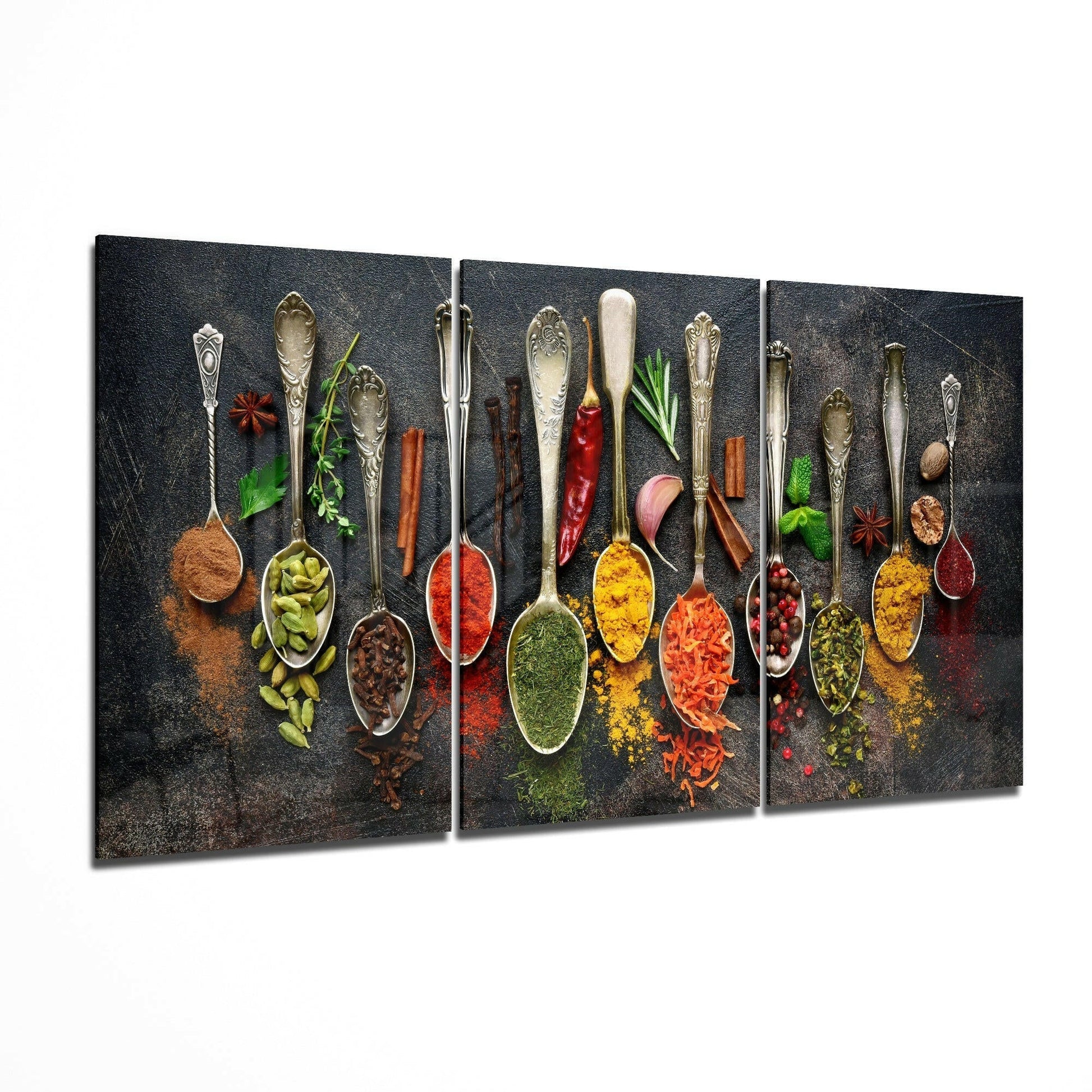 Three-panel glass art displaying ornate vintage spoons filled with colorful spices and fresh herbs on dark textured background.