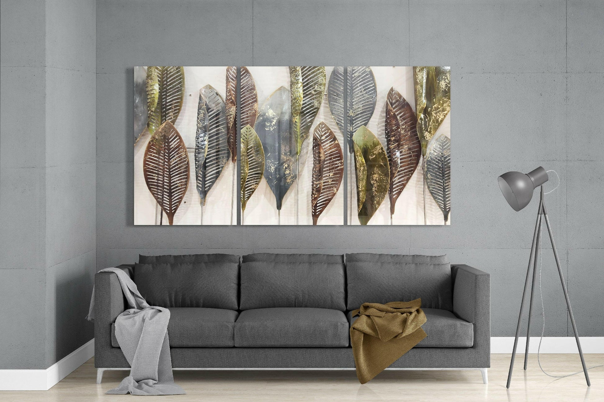 Triptych glass leaf artwork with gold, bronze, and black tones displayed above gray sofa in modern living room.