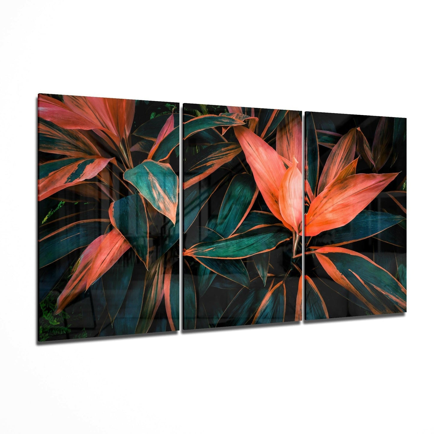 Three-panel triptych glass art displaying vibrant red-orange cordyline leaves with deep teal-green striping against dark background.