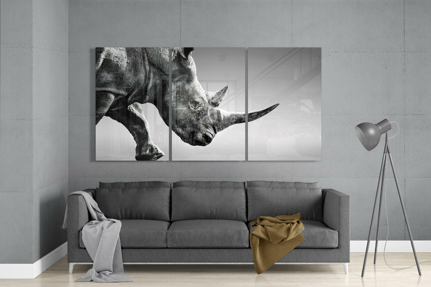 Three-panel black and white rhino glass art displaying close-up of rhino head and horns above gray sofa in modern living room.