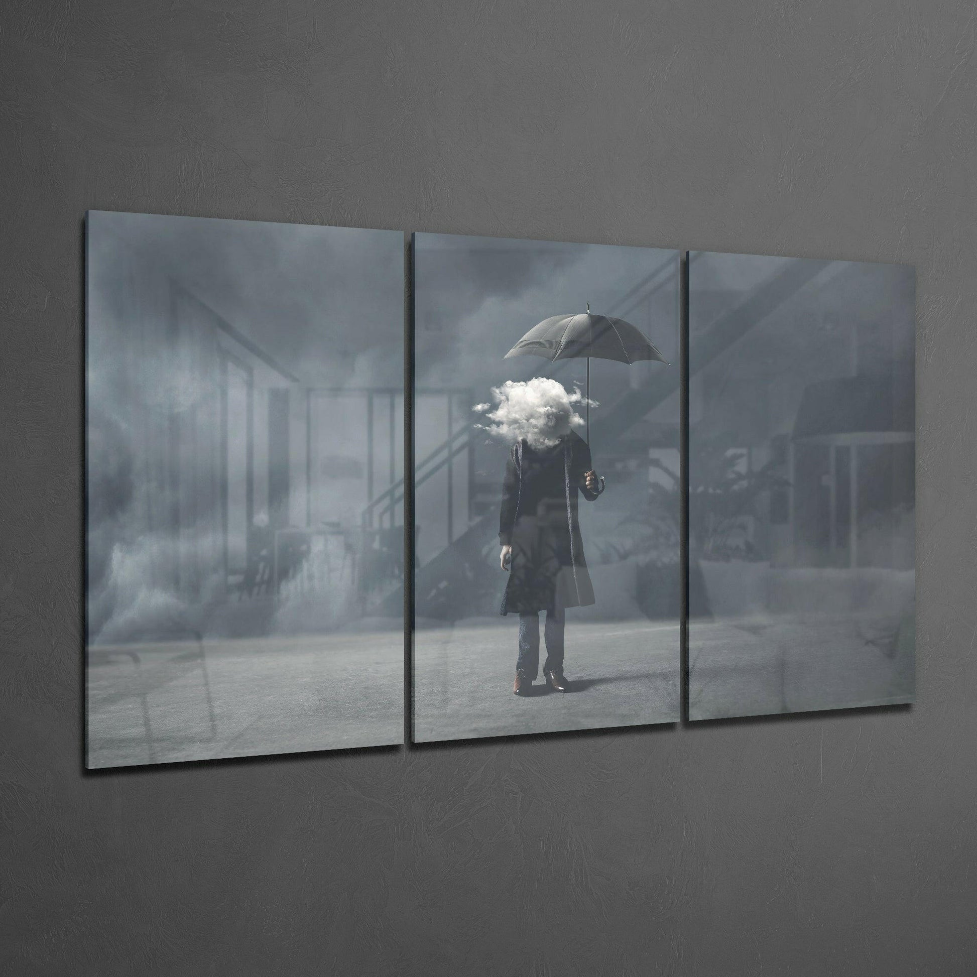 Three-panel glass art displaying a figure with umbrella holding a cloud, mounted on gray wall.