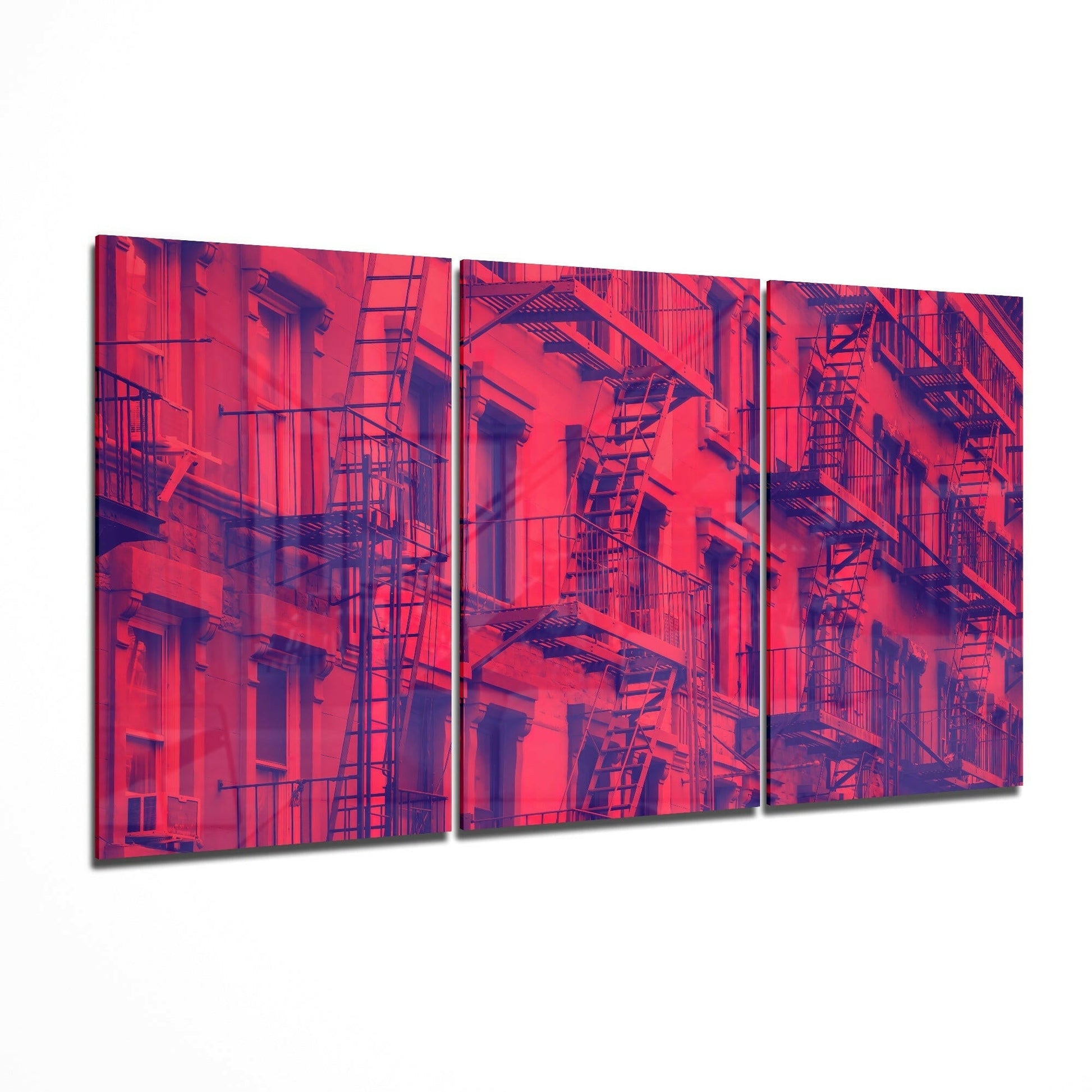 Three-panel glass art depicting a vivid red and purple-toned urban building facade with fire escapes and windows.
